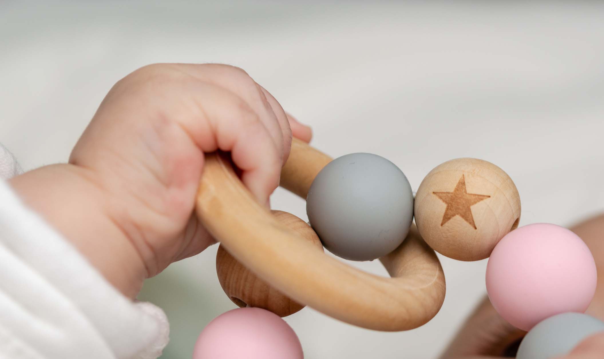 Close-up of a baby´s hand, playing with a wooden toy. Unfocused background Close-up of a baby´s hand, playing with a wooden toy. Unfocused background