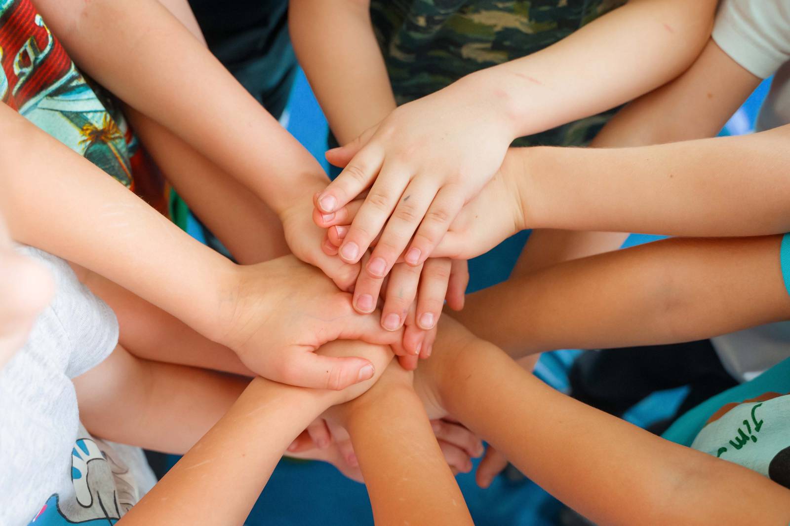 Children’s hands stacked together in a circle