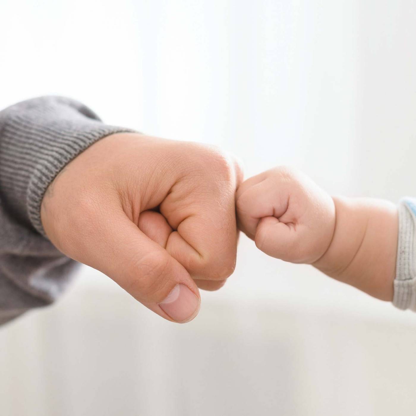 A baby’s hand holding a wooden teething ring with pastel silicone beads